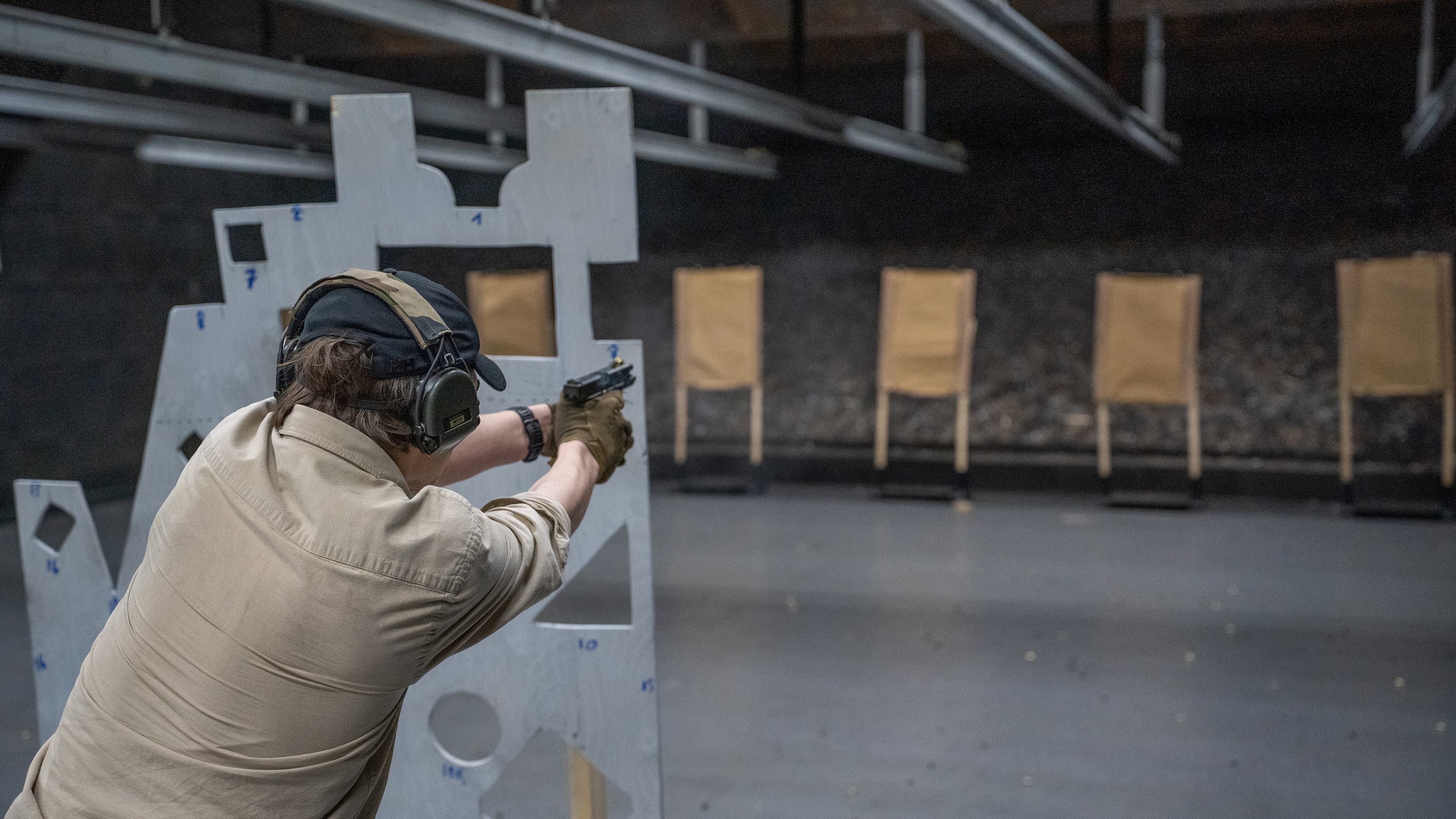 A participant practising pistol shooting through an indoor range barricade